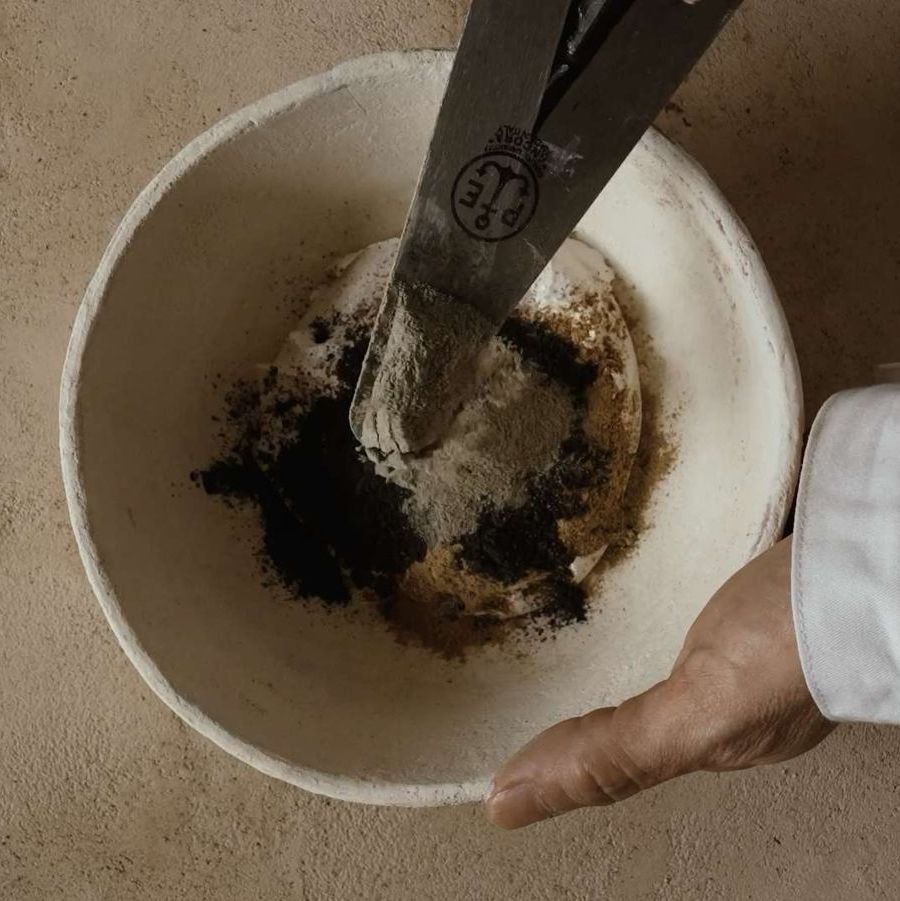 Mani di artigiano che miscelano l'impasto romano per Giorgetti