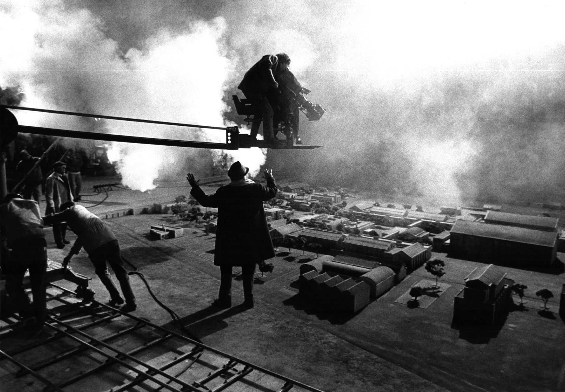 Set cinematografico in bianco e nero: un regista dirige la troupe davanti a un plastico di citt&agrave;, con la macchina da presa sul braccio della gru