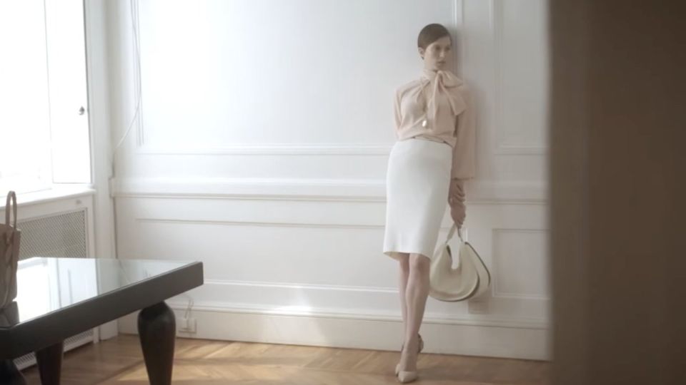 Modella con borsa bianca Borbonese in una stanza dalle pareti bianche