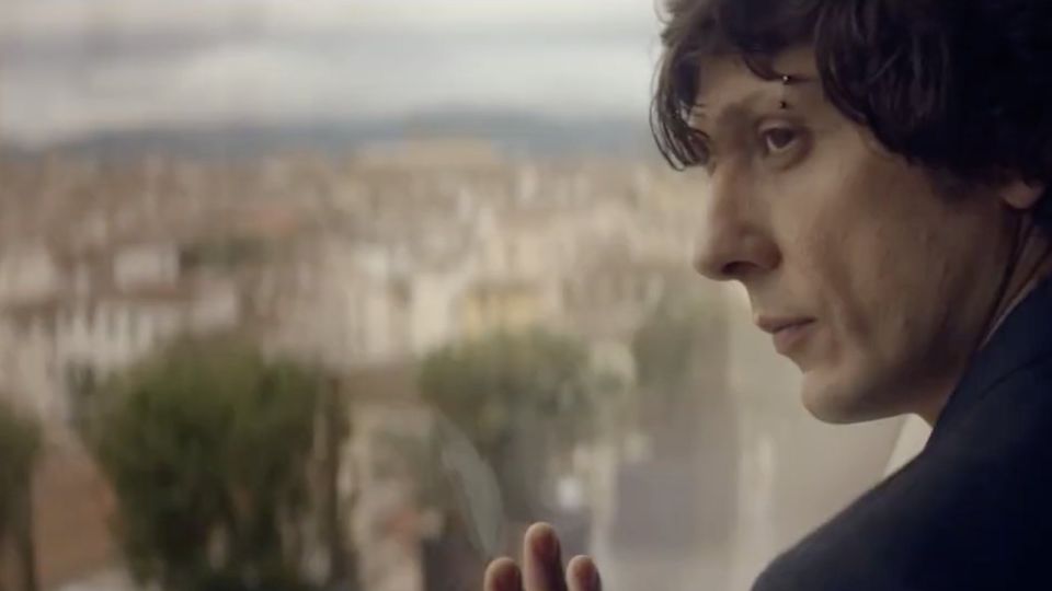 Ermal Meta alla finestra guarda i tetti di Firenze, dal fashion film Artes per Cuoio di Toscana