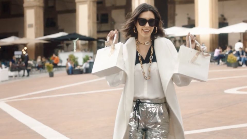 Ragazza con le borse della spesa Unoaerre in una piazza, spot Unoaerre